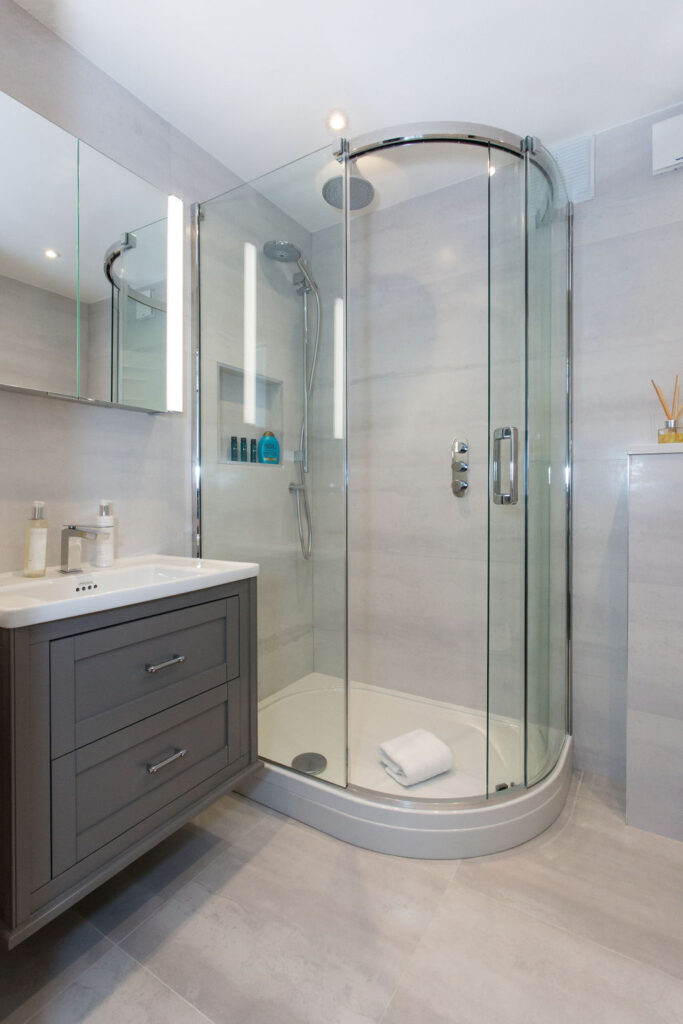 curved shower with screen next to bathroom cabinet